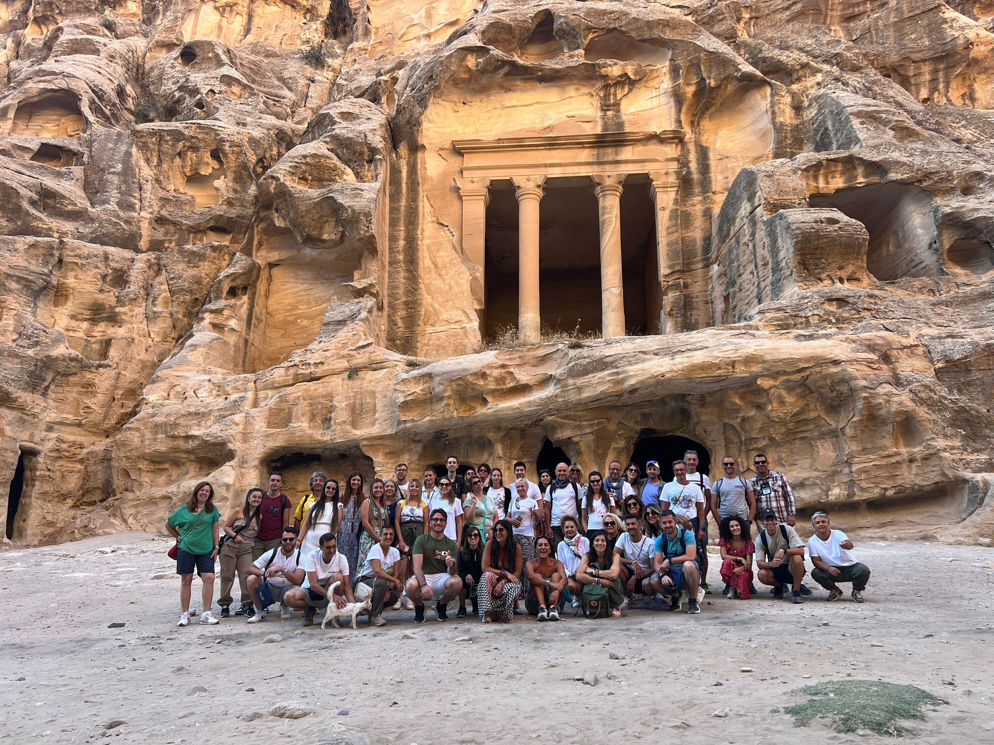 Gruppo di viaggiatori davanti al monumento scavato nella roccia di Petra, Giordania
